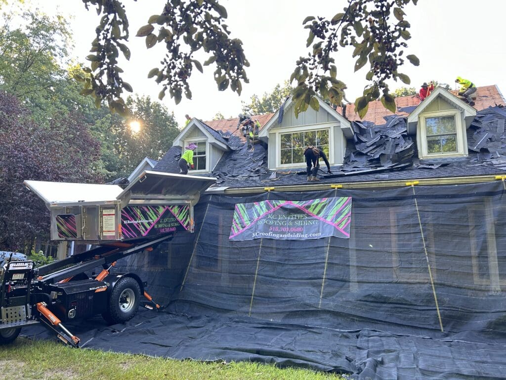 view of Catch-All protecting the property and Equipter raised to the roof for debris to be collected in while a roof is being replaced on a residential home