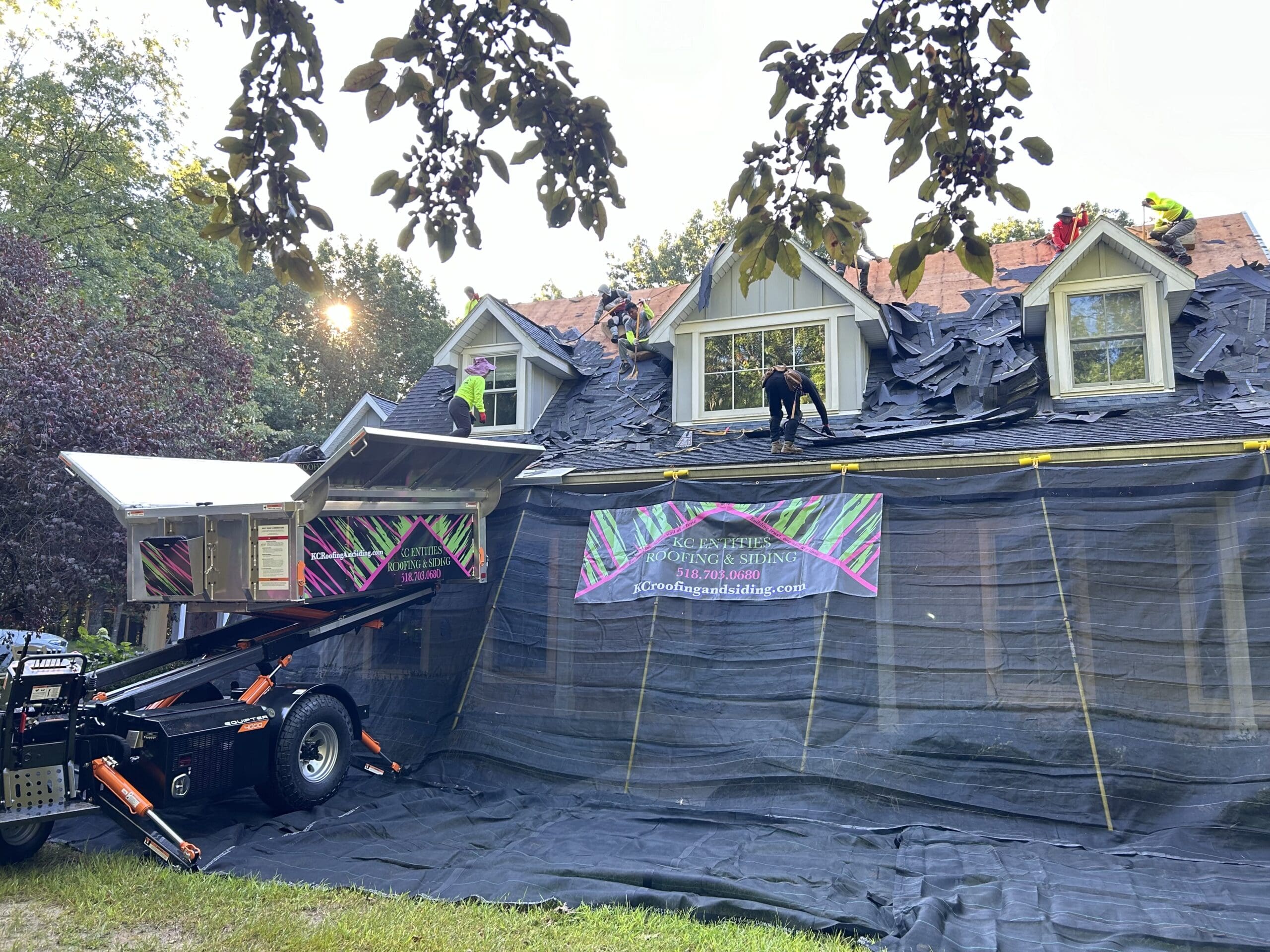 view of Catch-All protecting the property and Equipter raised to the roof for debris to be collected in while a roof is being replaced on a residential home