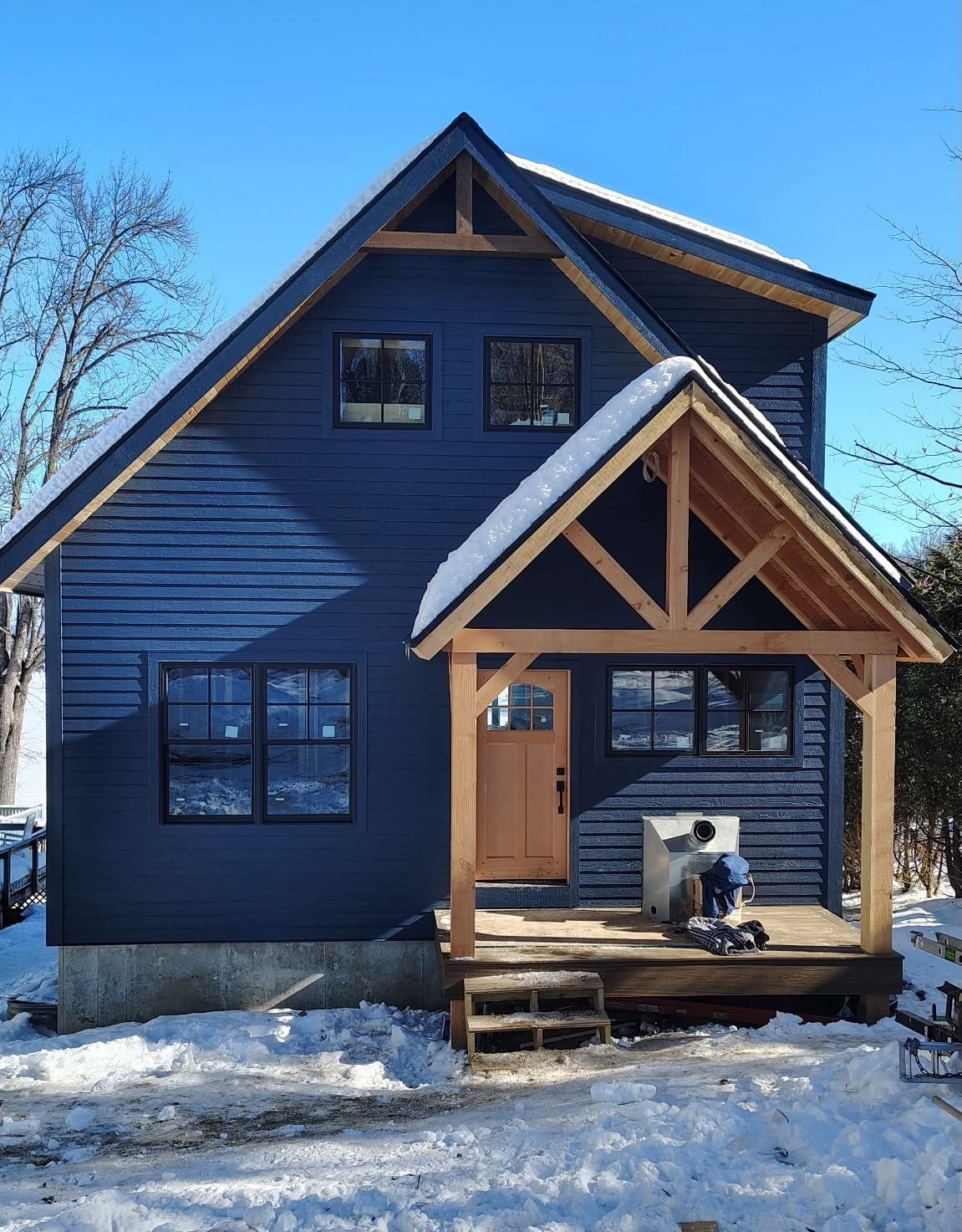Custom built house with new roof and siding during the winter months with snow on the roof and on the ground around the house