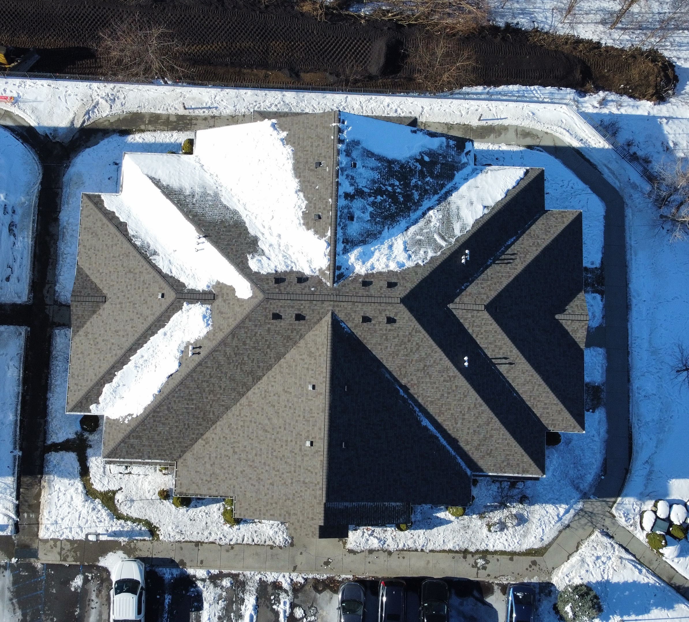 Aerial view of new Owens Corning Sandcastle asphalt shingles on an apartment building with snow on parts of the roof