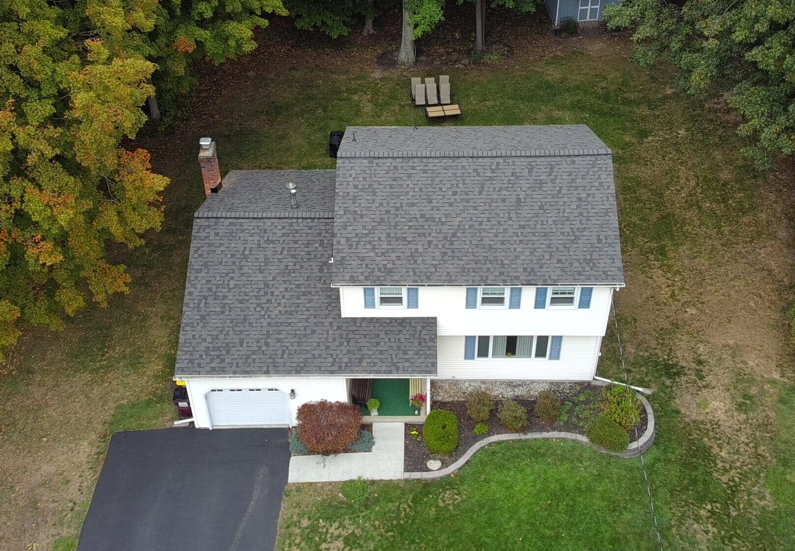 Aerial view of a house with a completed roof replacement with Owens Corning Peppercorn shingles