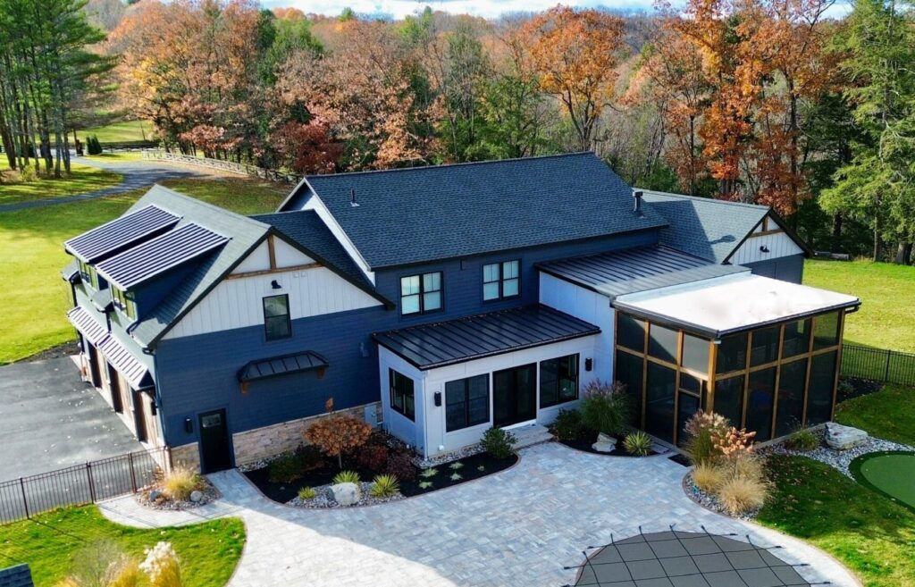 aerial view of residential house with asphalt shingles, metal roofing, and EPDM and TPO on flat roof.