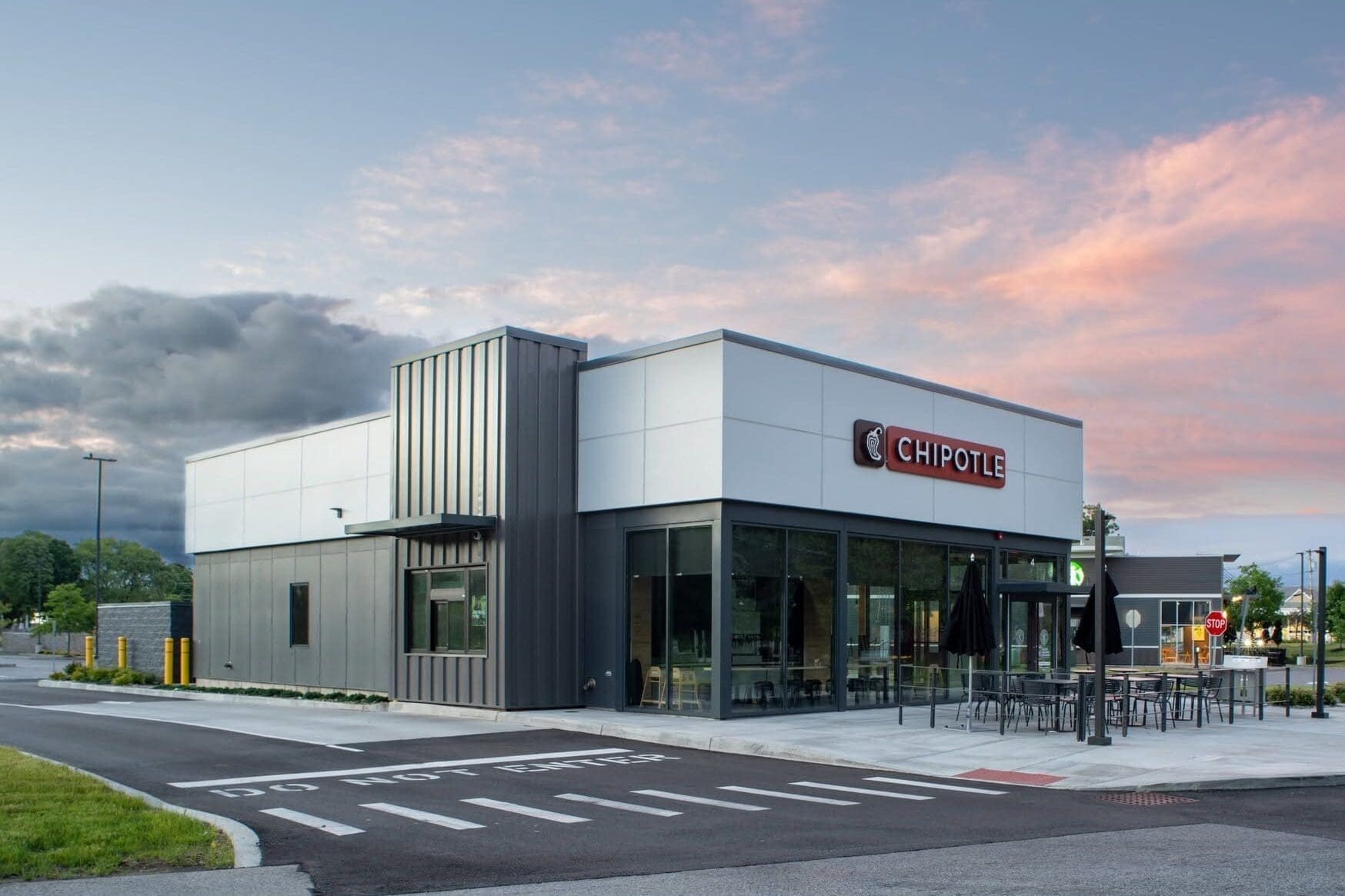 new chipotle building in Malta, New York with signage on the front and side, and a sunset in the background