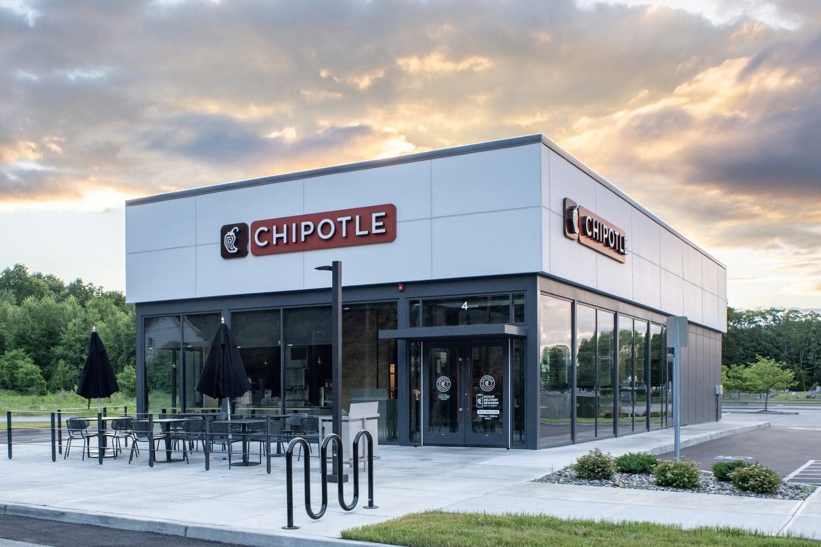 new chipotle building in Malta, New York with signage on the front and side, and a sunset in the background
